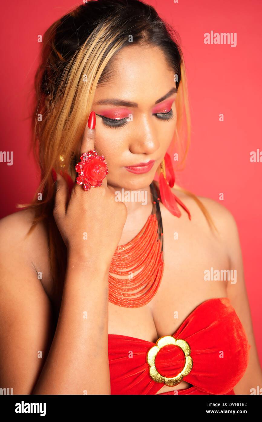 La splendida donna con abito rosso si pone elegantemente per ritratti Foto Stock