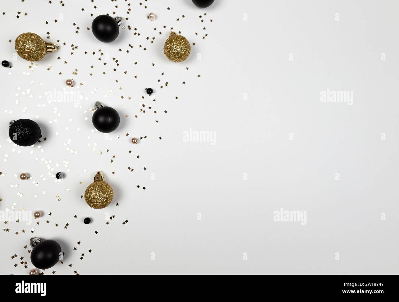 Composizione natalizia, decorazioni in oro e nero, baule in oro e nero, coriandoli con stelle dorate su sfondo bianco. Foto Stock