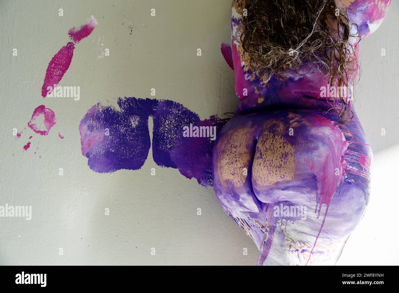 La parte posteriore e inferiore di una bella donna nuda grassa in sovrappeso, paffuta bodypainting di colore rosa, viola, bianco e blu, che ha lasciato un grasso bot Foto Stock