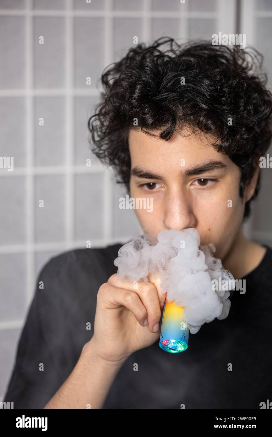 Regno Unito per vietare vapes usa e getta (e-sigarette) per proteggere la salute dei bambini. Ragazzo adolescente con vapori monouso e vapori monouso fumanti Foto Stock
