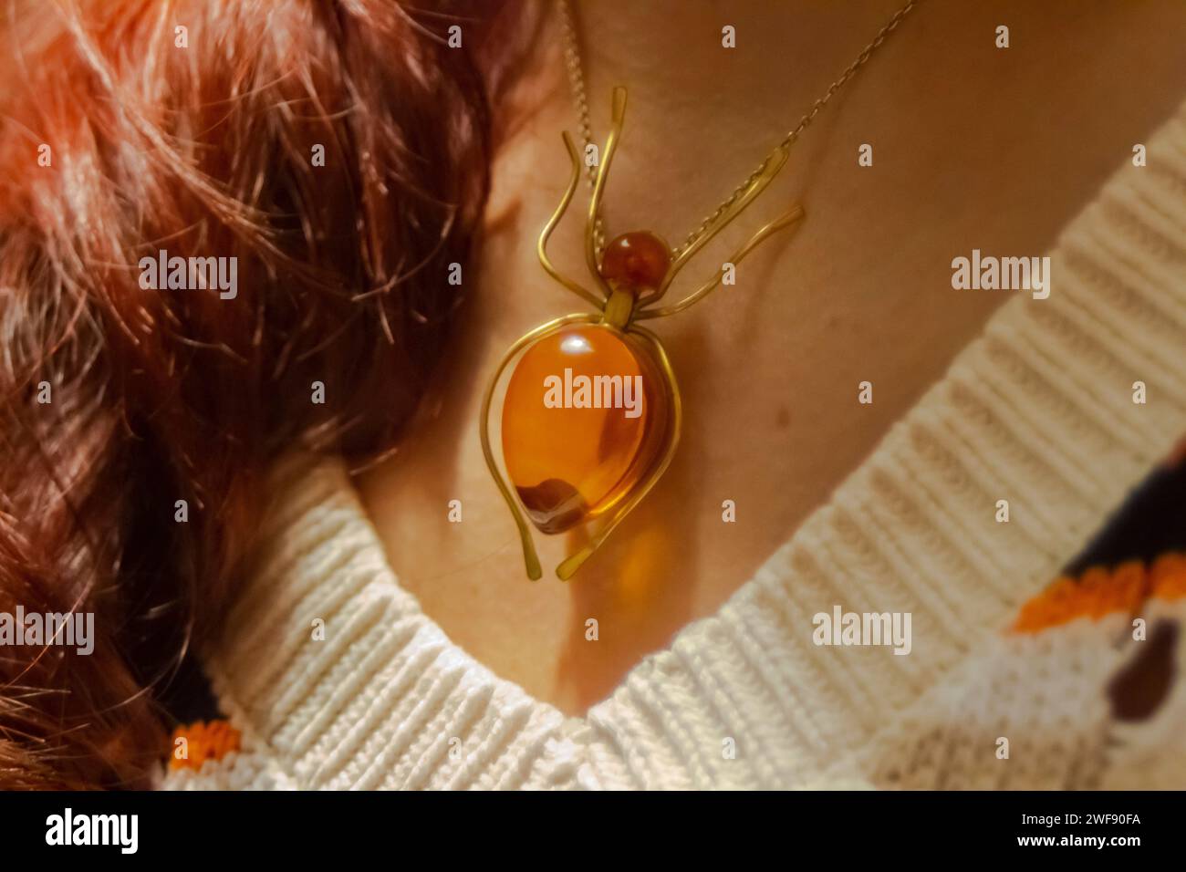 Donna che indossa un'elegante collana in filo d'oro decorata con un vivace perline di vetro arancione Foto Stock