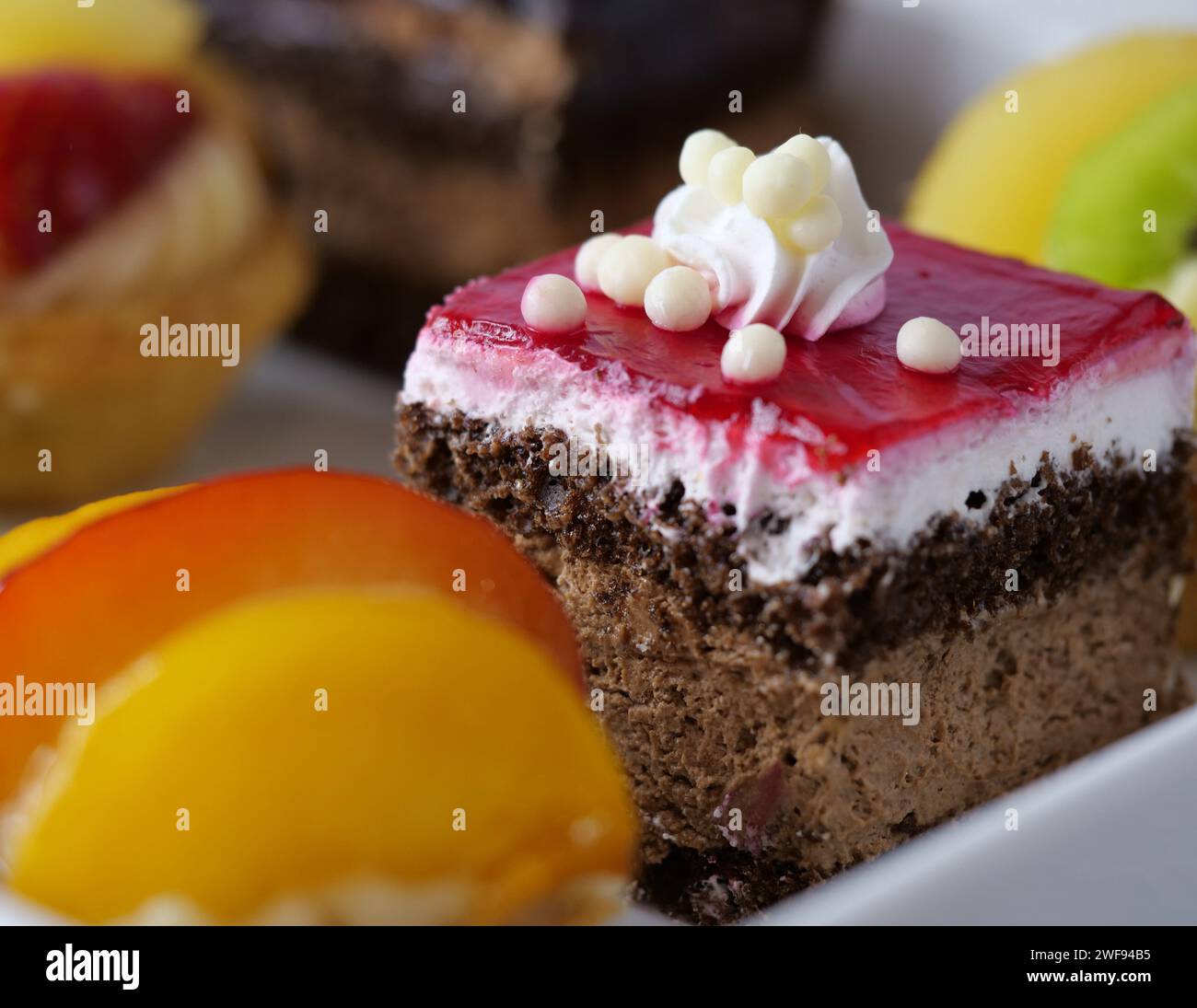 Una varieta' di deliziosi dessert splendidamente disposti su un piatto bianco incontaminato, accompagnati da una frutta vibrante e succulenta Foto Stock