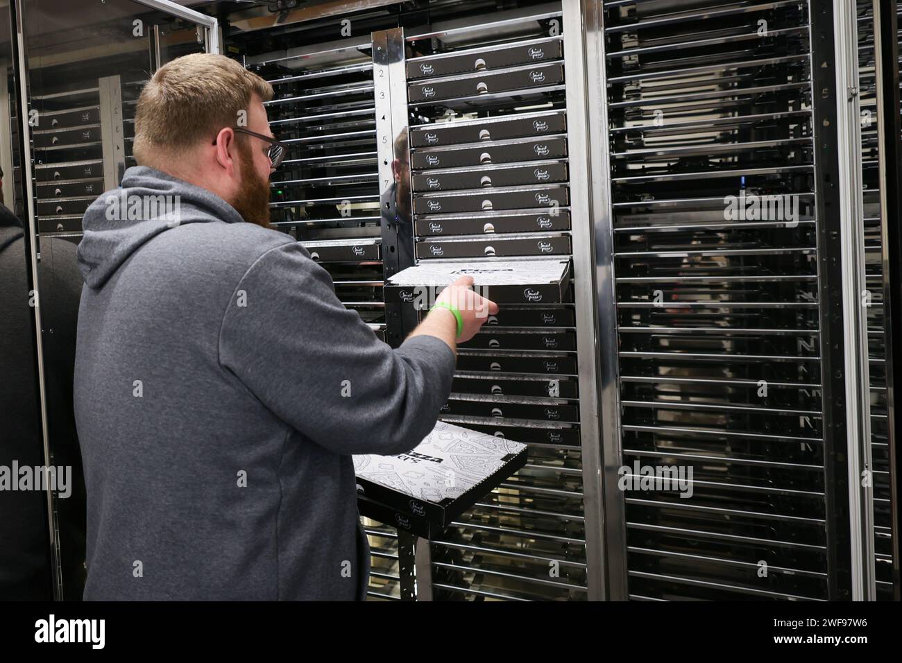 PRODUZIONE - 07 dicembre 2023, Schleswig-Holstein, Grömitz: Un dipendente sente i vani frigoriferi di un distributore automatico di pizza in un chiosco di distributori automatici sul lungomare. Foto: Christian Charisius/dpa Foto Stock