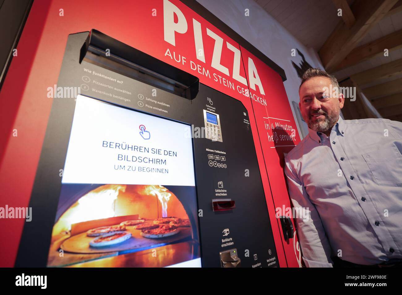 PRODUZIONE - 07 dicembre 2023, Schleswig-Holstein, Grömitz: Patrick Enste, Project Manager presso gli hotel Lieblingsplatz, si trova in una macchina per la pizza in un chiosco di distributori automatici sul lungomare. Foto: Christian Charisius/dpa Foto Stock