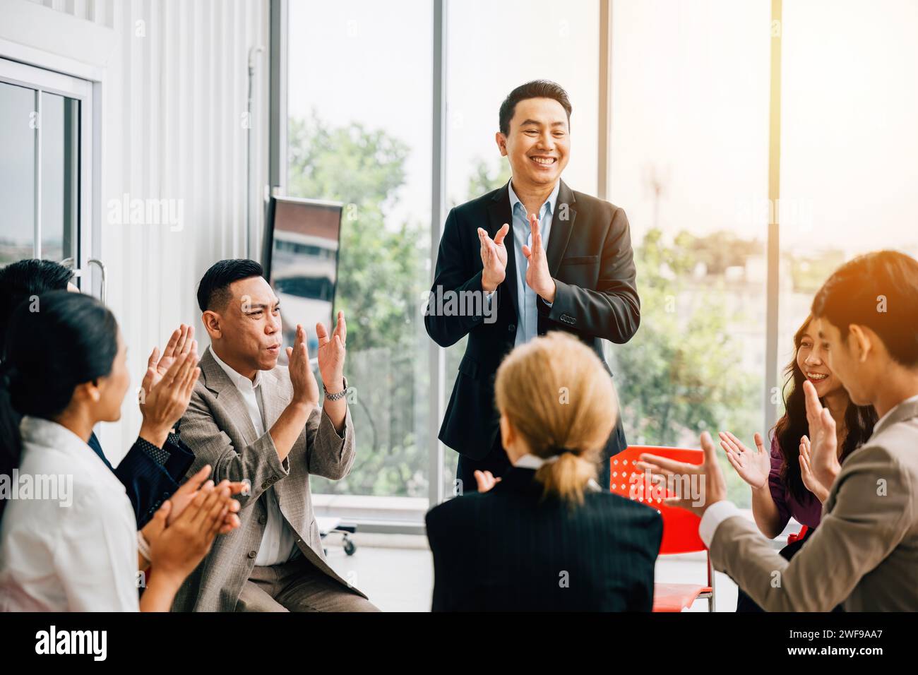 Durante un seminario, un insegnante spiega le strategie e il pubblico diversificato alza le mani per chiedere Foto Stock