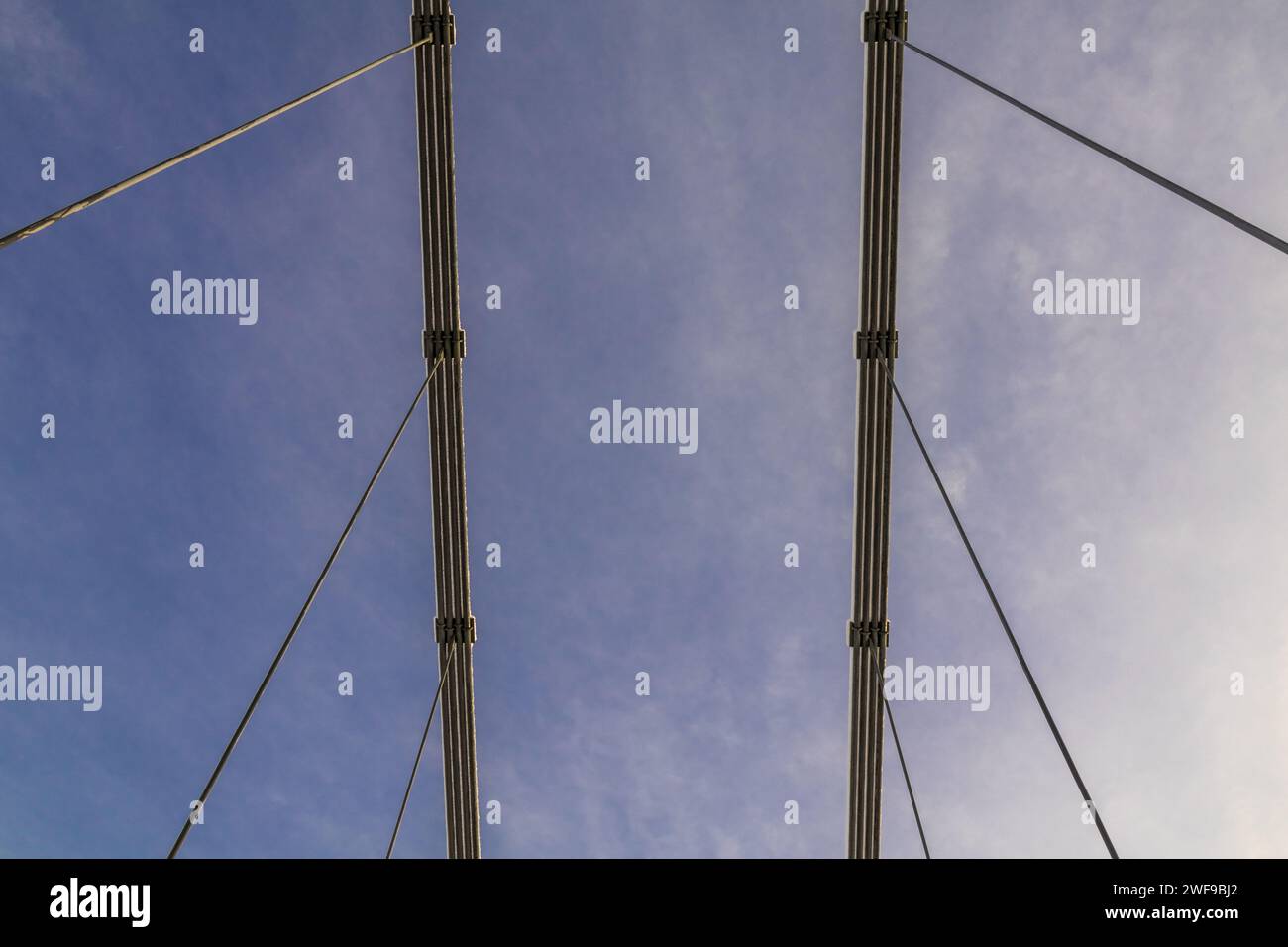 Skybound Symphony: Angoli astratti di cavi in acciaio sospesi creano una danza geometrica che collega terra al cielo in un ponte di linee Foto Stock