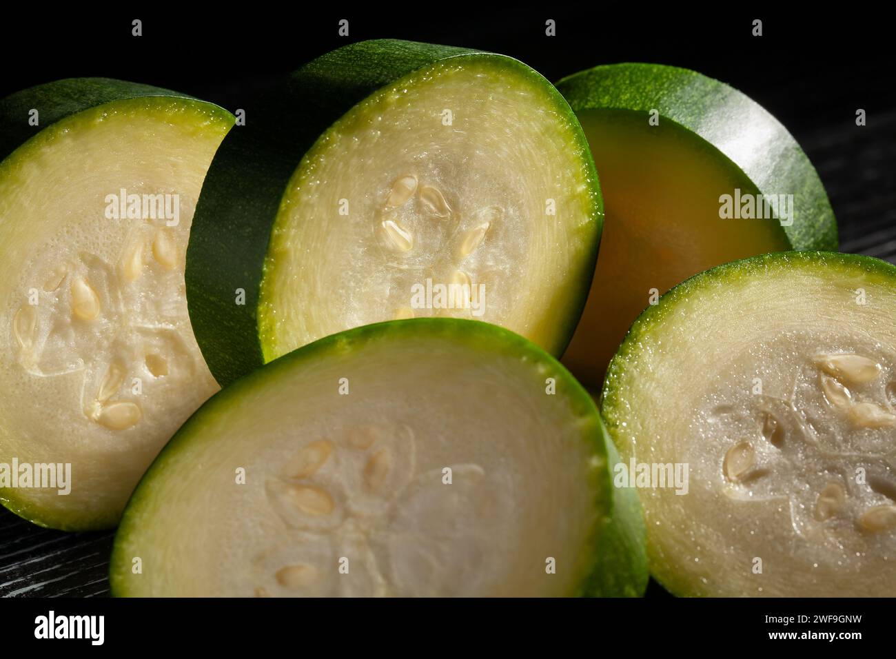 fette di zucchine su sfondo nero Foto Stock