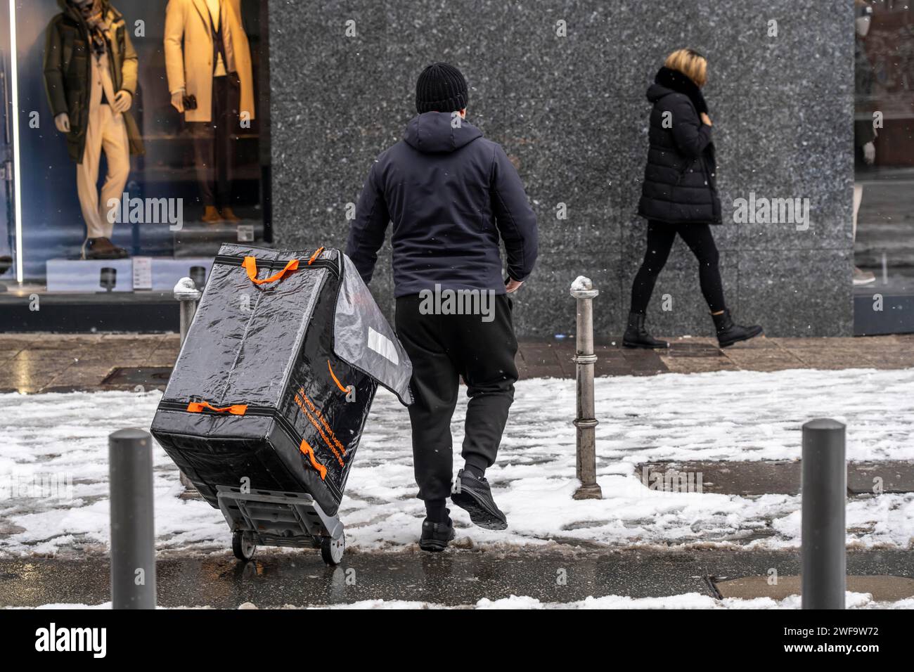 Inverno a Francoforte, il dipendente Amazon consegna una spedizione al cliente, a piedi, nel distretto bancario di Assia, in Germania Foto Stock