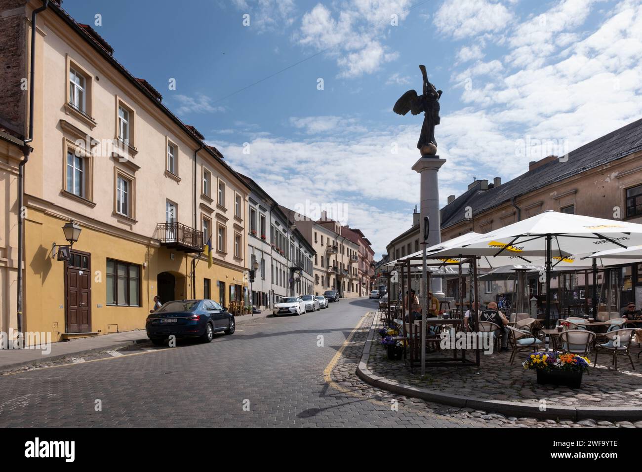 Paesaggio urbano di Vilnius in via Užupio con case colorate e turisti su una terrazza coperta, vicino alla statua "Angelo di Užupis" Foto Stock
