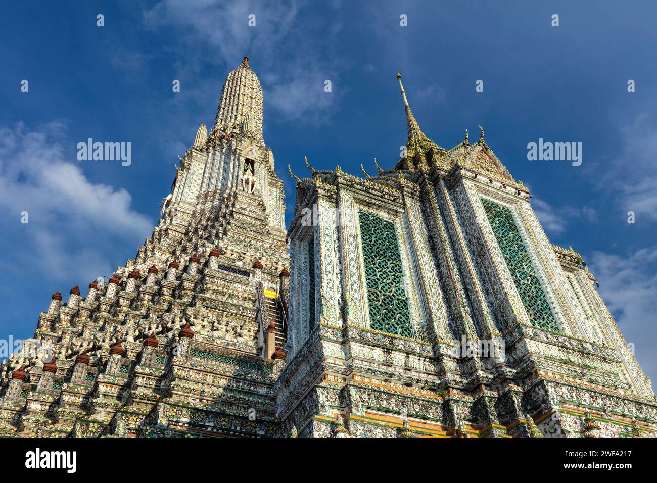 Torreggiante prang e edificio adiacente al Wat Arun (Tempio dell'Alba), Bangkok, Thailandia. Progetti complessi su entrambi. Cielo blu e nuvole sopra. Foto Stock