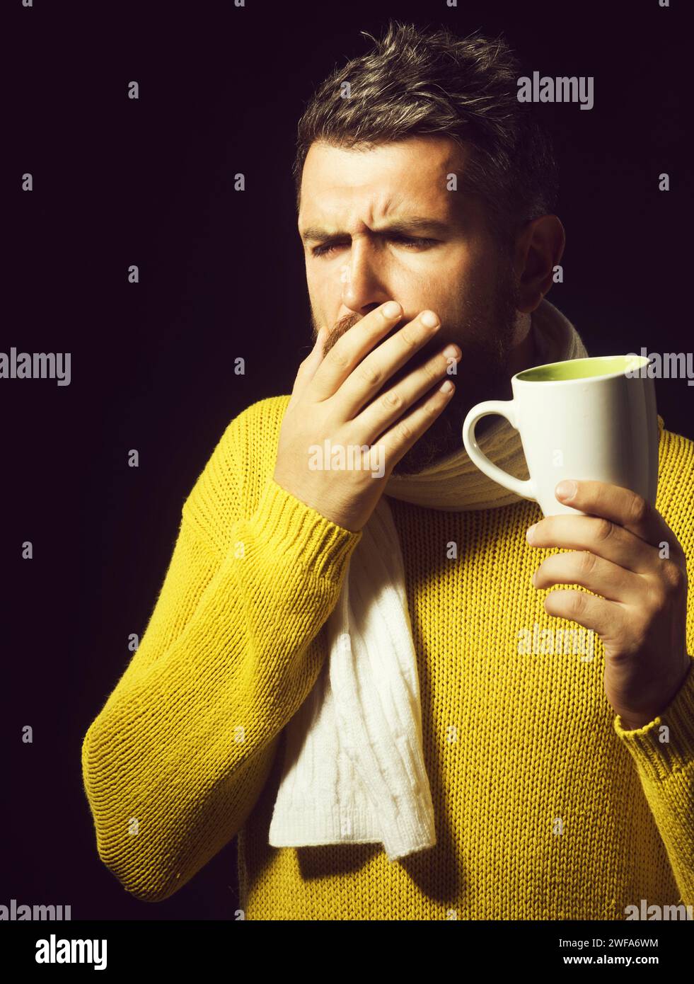 Uomo malbarbato con influenza e febbre che beve tè curativo. Uomo malvagio che tossisce. Trattamento e assistenza sanitaria. Bel ragazzo che ha mal di gola. Uomo malato dentro Foto Stock