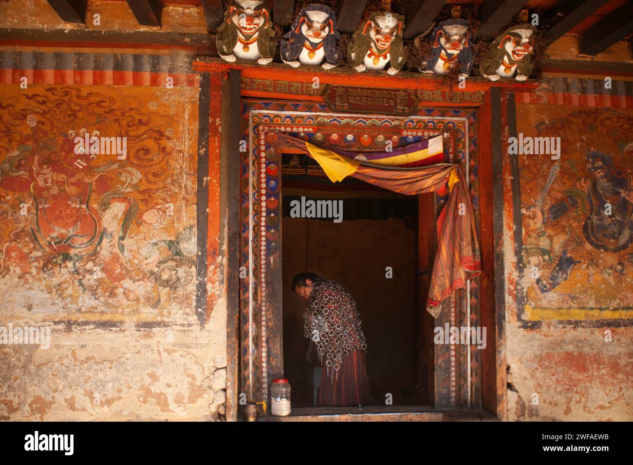 L'uomo bhutanese porta una posta di ferro per la penitenza, un atto tradizionale che la gente del posto si impegna al tempio Tamshing Lhakhang, nella Valle di Bumthang, in Bhutan Foto Stock