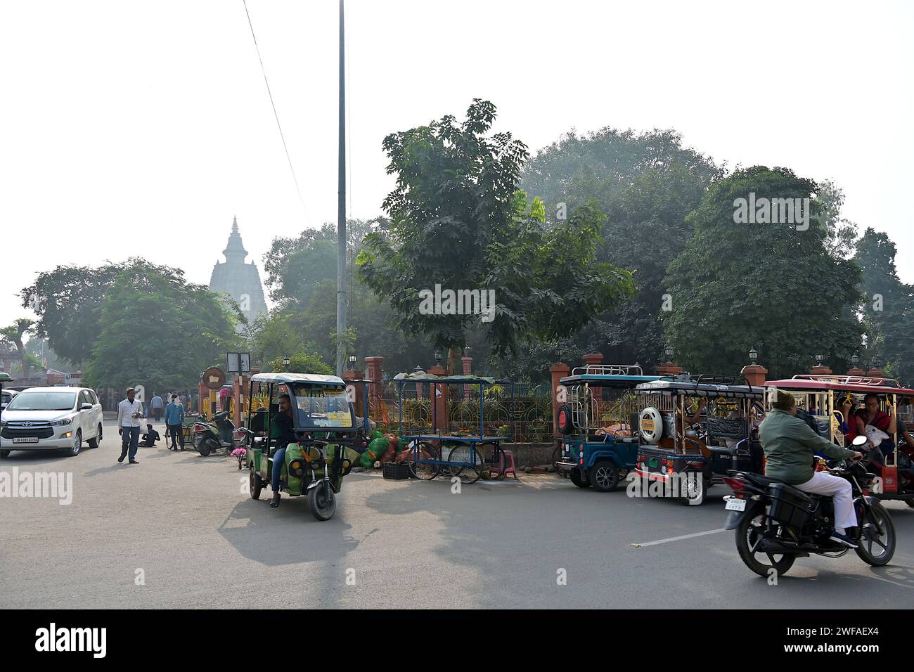 Scena di Bodhgaya Street con taxi e-risciò e la cupola del Tempio Mahabodhi sullo sfondo Foto Stock