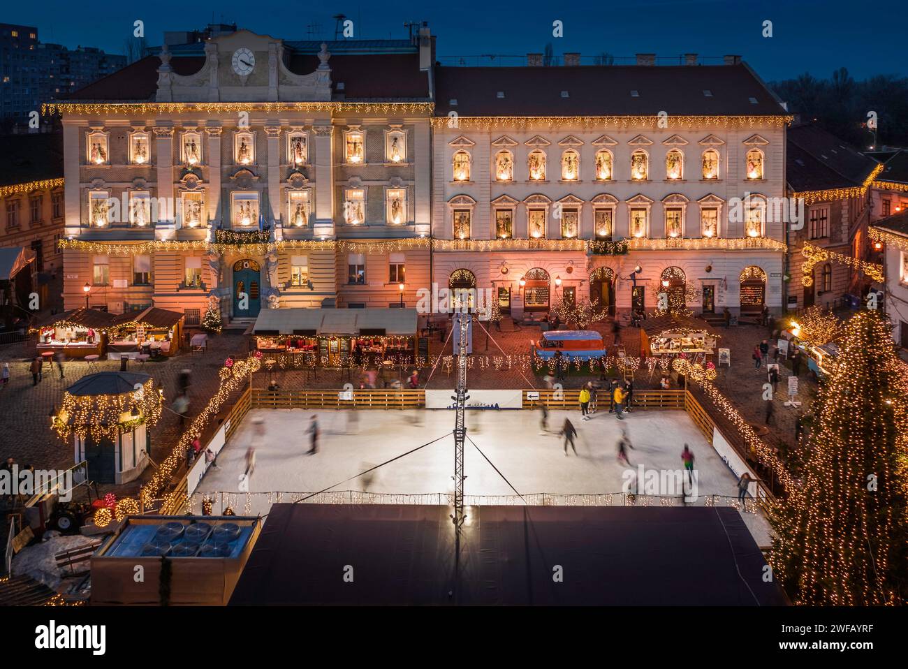 Budapest, Ungheria - veduta aerea del mercato di Natale e della pista di pattinaggio su ghiaccio in piazza Szentlelek, Obuda al tramonto. Negozi decorativi illuminati, decorazioni festive Foto Stock