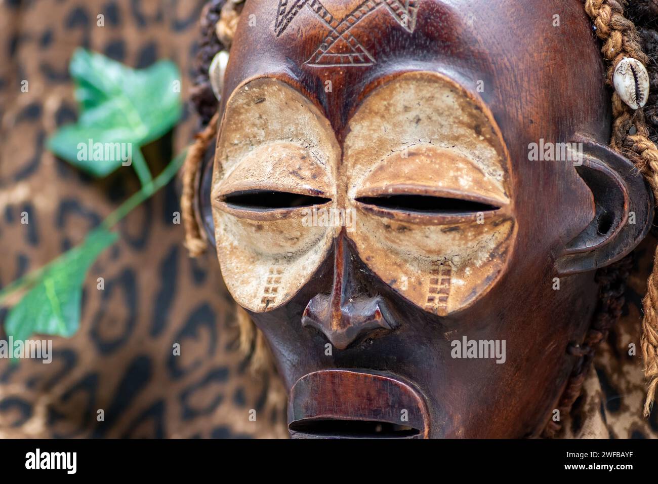 Maschera africana tribale in legno dall'Uganda, per la famiglia o la protezione personale, realizzata in legno locale, corde e conchiglie come decorazione dei capelli Foto Stock
