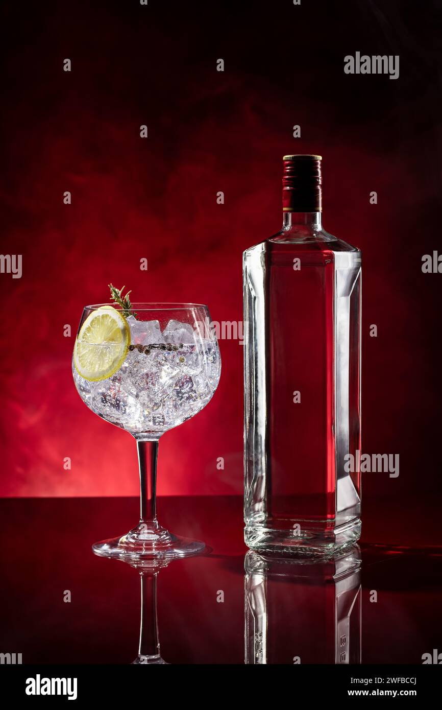 Gin tonic su sfondo rosso con fumo e spazio coperto. Formato verticale. Foto Stock