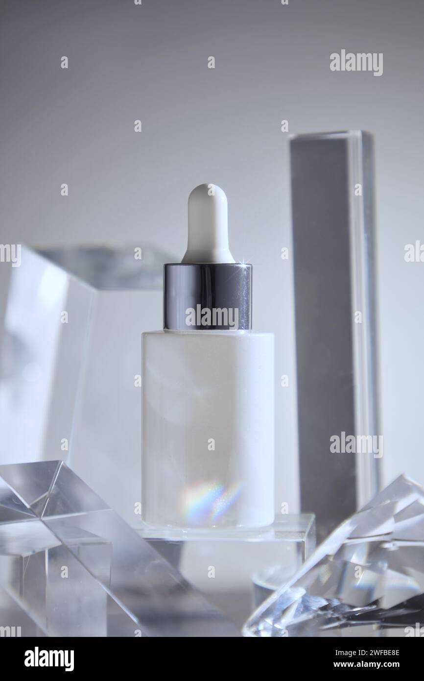 Scena minimalista di una bottiglia bianca con contagocce decorata con un oggetto trasparente in vetro dalle forme geometriche. Bellezza, prodotti per la cura della pelle mockup con canapa Foto Stock