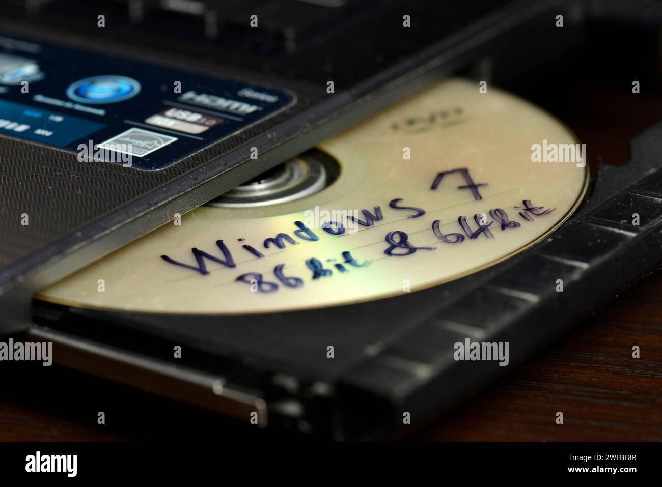 Concetto di installazione illegale del software Windows con Windows 7 a 86 bit e 64 bit crack su CD pronto per essere inserito in un'unità masterizzatore del computer portatile per l'installazione Foto Stock