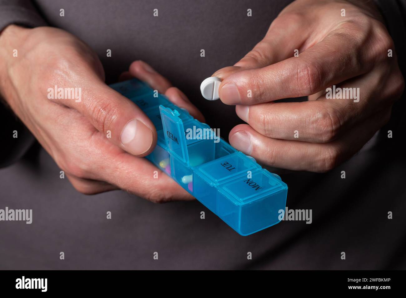 L'uomo prende le pillole dalla scatola. Assistenza sanitaria e concetto di vecchiaia con farmaci. Medicinali sul tavolo Foto Stock