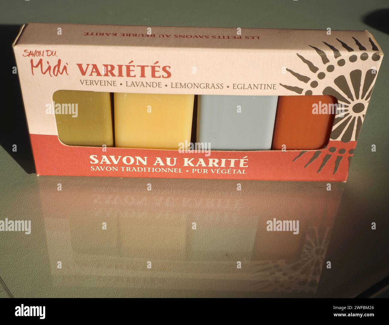 Confezione variegata di 4 saponi ospiti con profumi di verbena, lavanda, citronella e rosa selvatica. “Savon au karité”, sapone burro di karité. Immagine riflessa nel vetro. Foto Stock