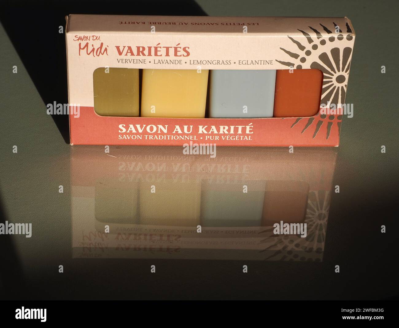 Confezione variegata di 4 saponi ospiti con profumi di verbena, lavanda, citronella e rosa selvatica. “Savon au karité”, sapone burro di karité. Immagine riflessa nel vetro. Foto Stock