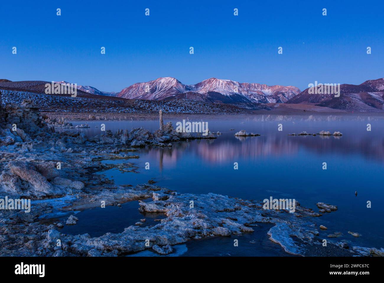 Prima dell'alba nebbia sulle formazioni di tufo sul lago Mono in California. Le montagne della Sierra orientale sono dietro. Foto Stock