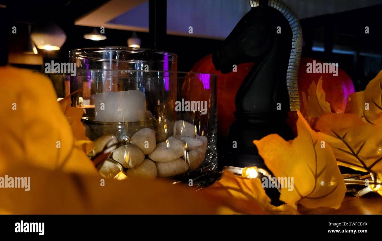 splendido decor, una magnifica composizione che include candele con pietre in un vaso di vetro, un grande cavaliere scacchistico, foglie d'acero, illuminate da un ga Foto Stock