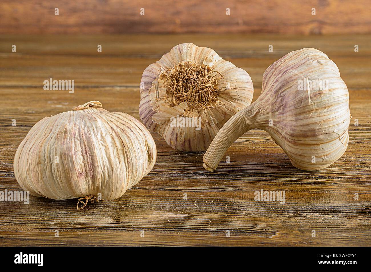 Tre bulbi all'aglio su un tavolo rustico in legno con uno sfondo vintage Foto Stock