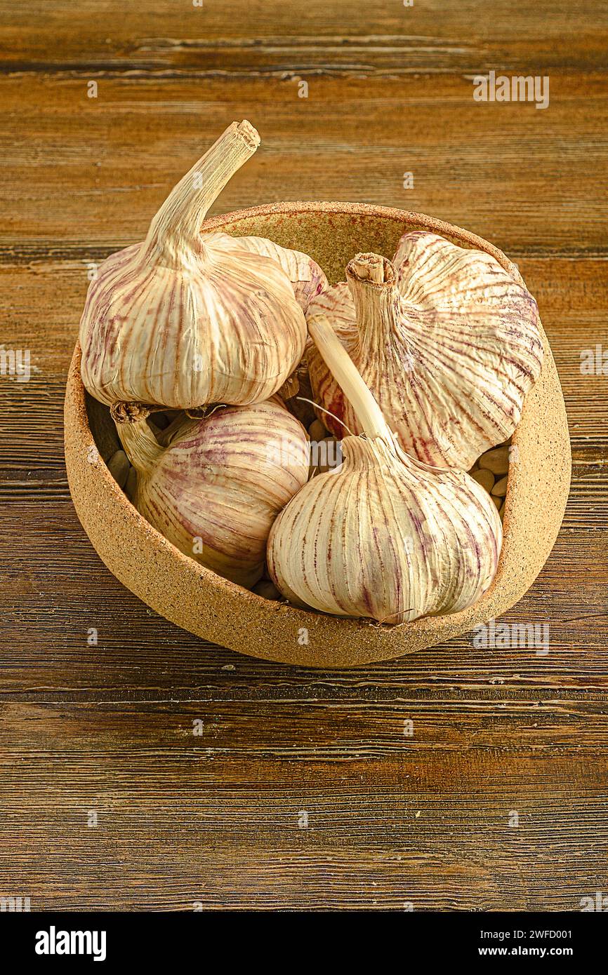 Alcuni tipi di aglio in un recipiente poggiato su una superficie rustica in legno Foto Stock