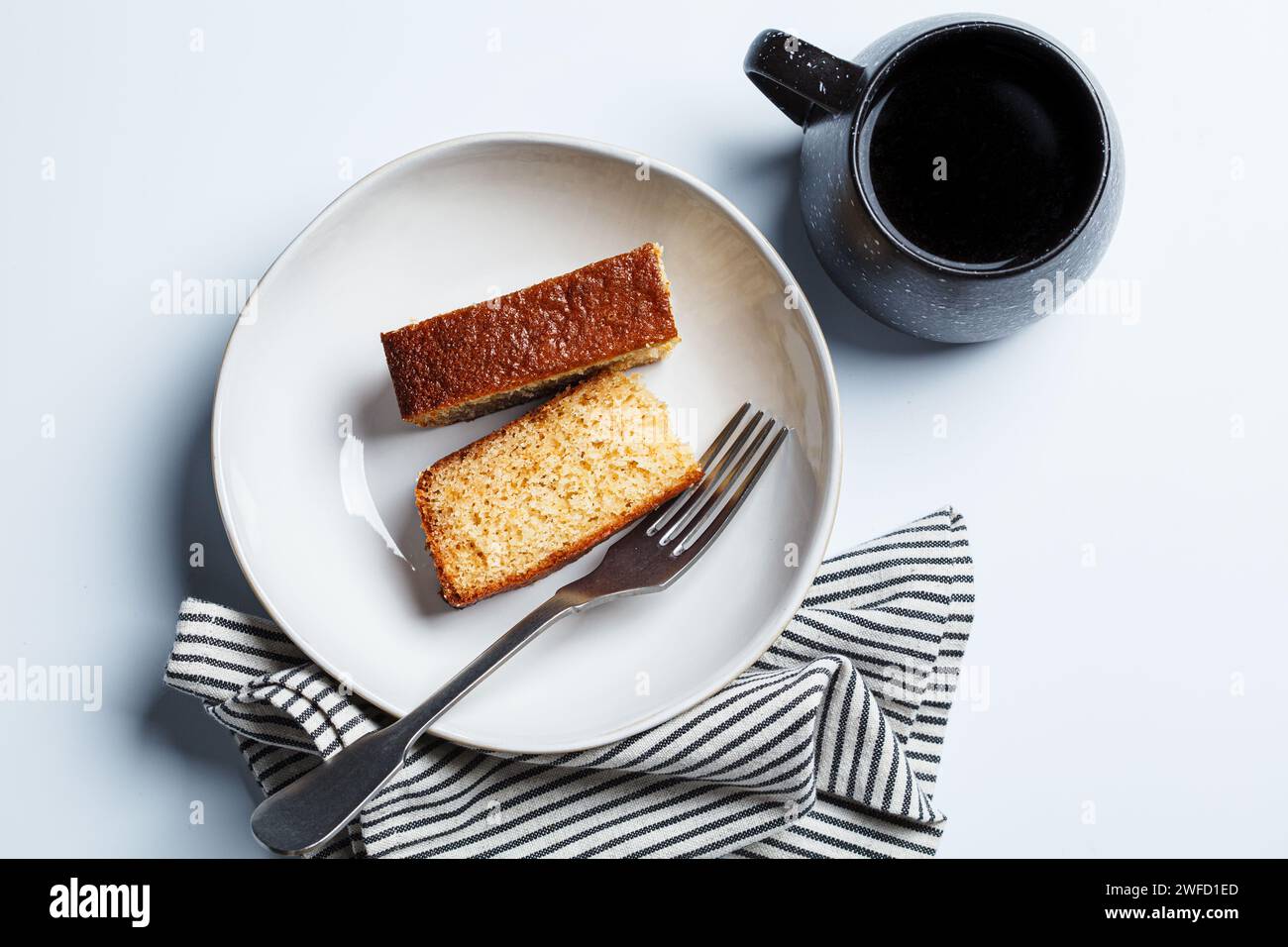 Pezzi di torta da colazione con agrumi e una tazza di caffè con sfondo bianco. Foto Stock