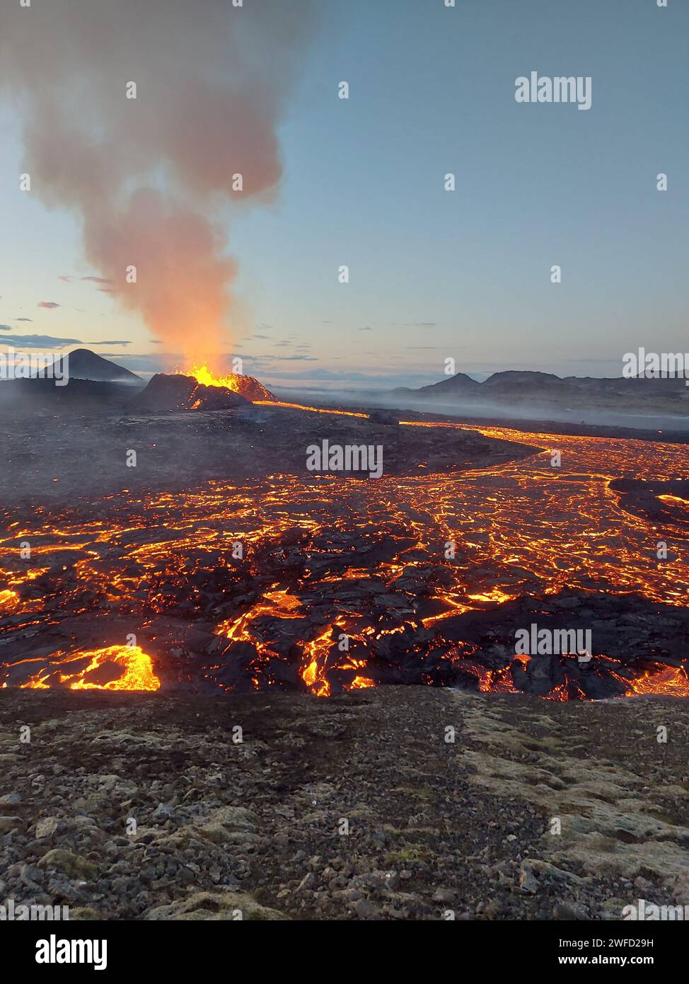 La vista di un vulcano in eruzione circondato da lava luminosa. Islanda Foto Stock