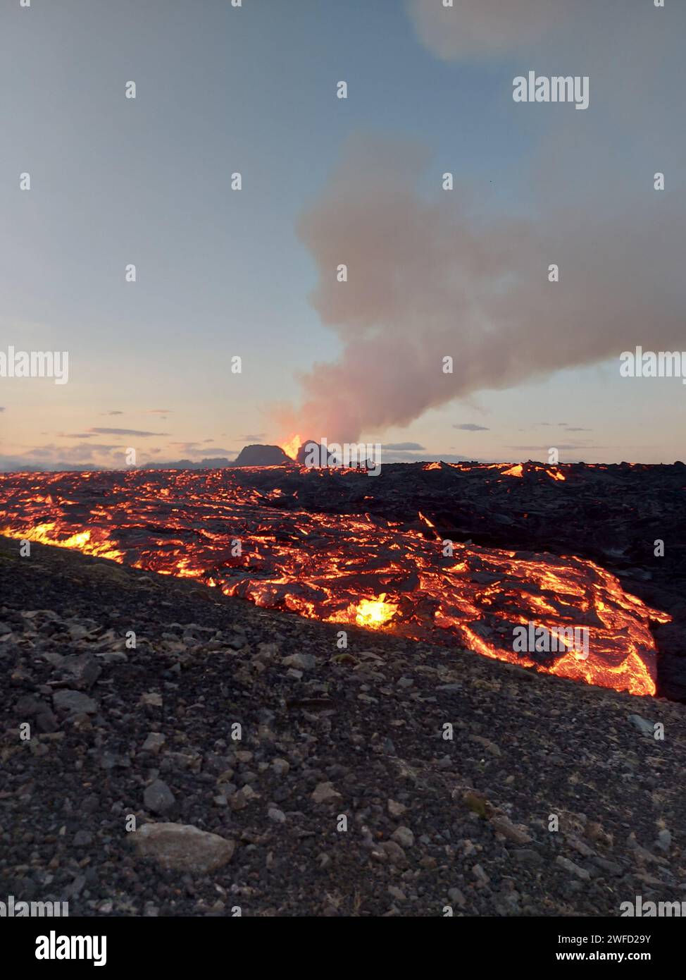 La vista di un vulcano in eruzione circondato da lava luminosa. Islanda Foto Stock