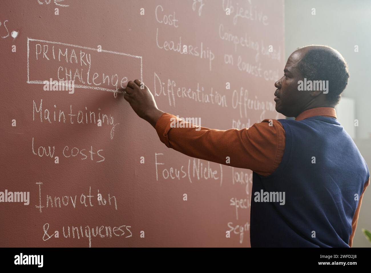 Ritratto laterale di un professore universitario afroamericano che scrive su lavagna mentre si prepara per la lezione al college Foto Stock