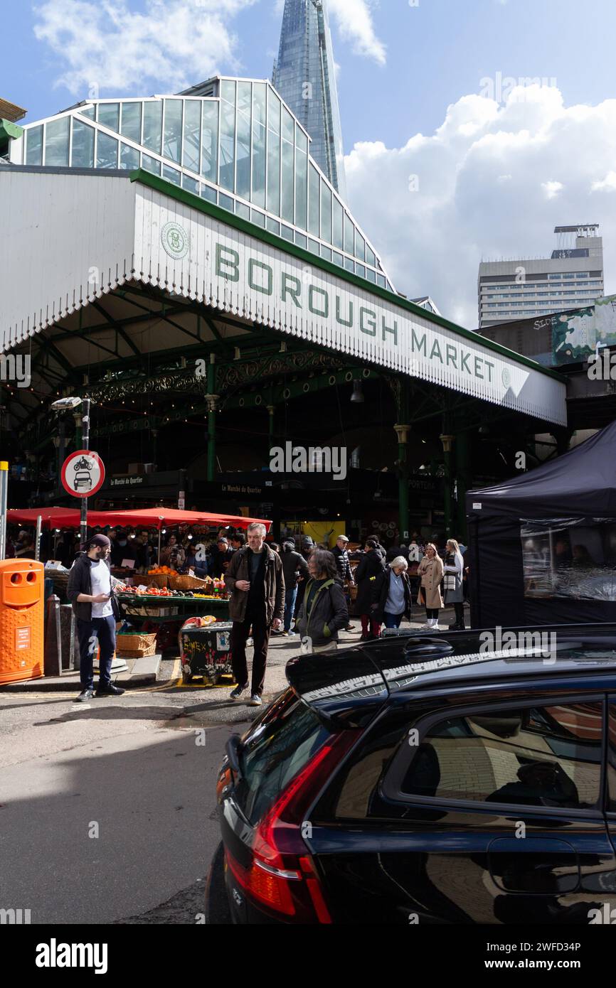 L'ingresso del Borough Market con The Shard sullo sfondo in una giornata luminosa e soleggiata a Londra, Regno Unito. Le bancarelle sono visibili nella parte anteriore e le persone sono S Foto Stock