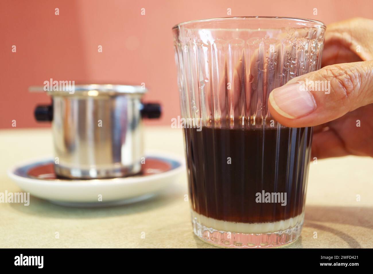 Primo piano della mano con un bicchiere di caffè americano vietnamita appena fatto Foto Stock