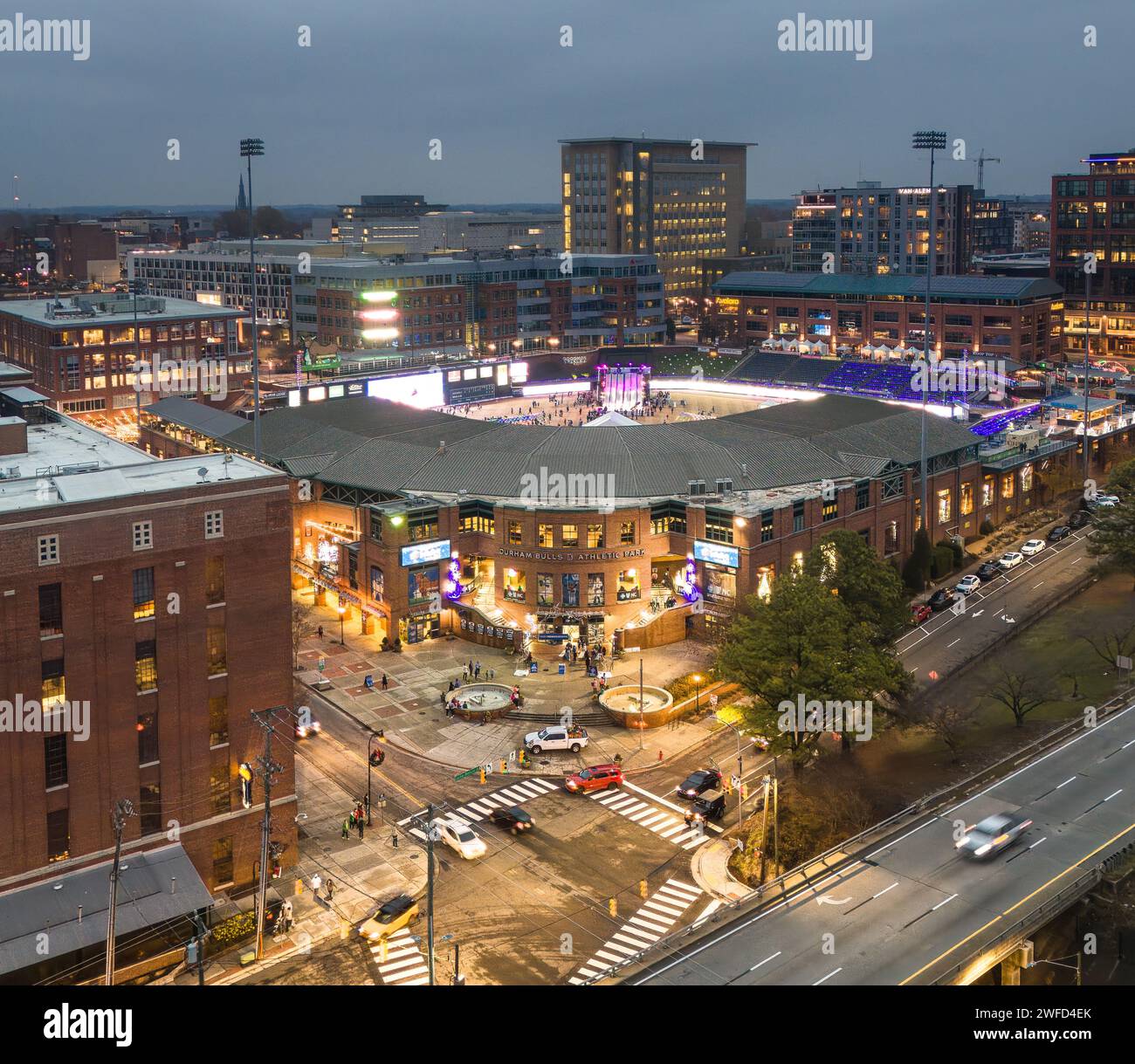 Strada cittadina di notte con uno stadio illuminato in modo brillante Foto Stock