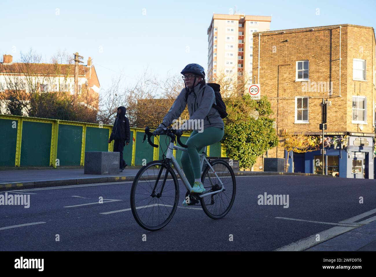 Una motociclista di sesso femminile si sposta ad Hackney al sole della mattina presto d'inverno. Foto Stock