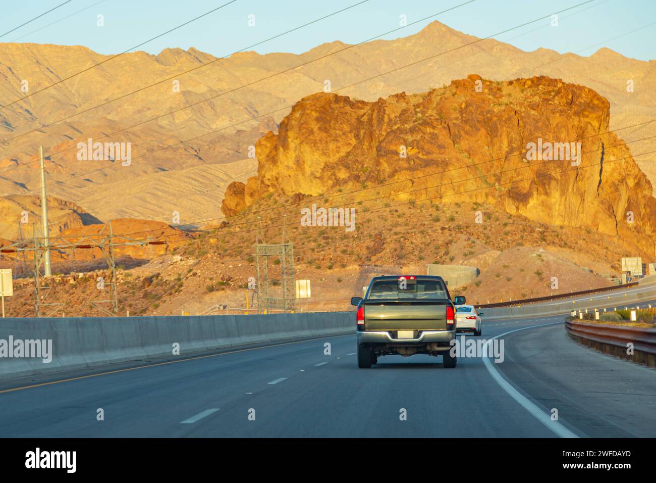 Autostrada americana con auto. La strada si estende in lontananza sullo sfondo di montagne. Guida in auto lungo l'autostrada, vista posteriore Foto Stock