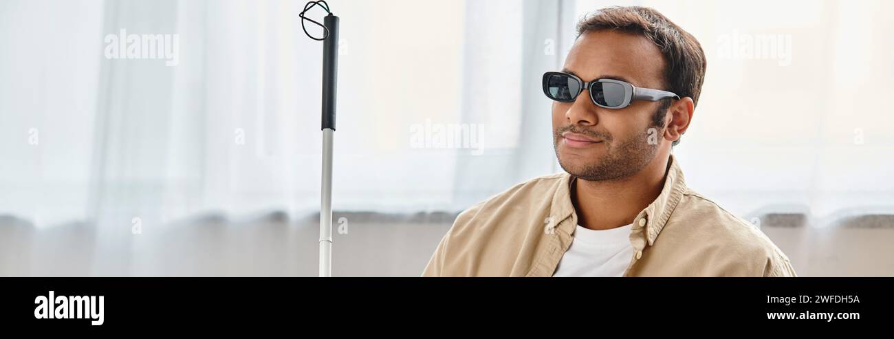 gioioso uomo indiano con cecità in un intimo abbigliamento quotidiano con occhiali e bastone da passeggio, banner Foto Stock