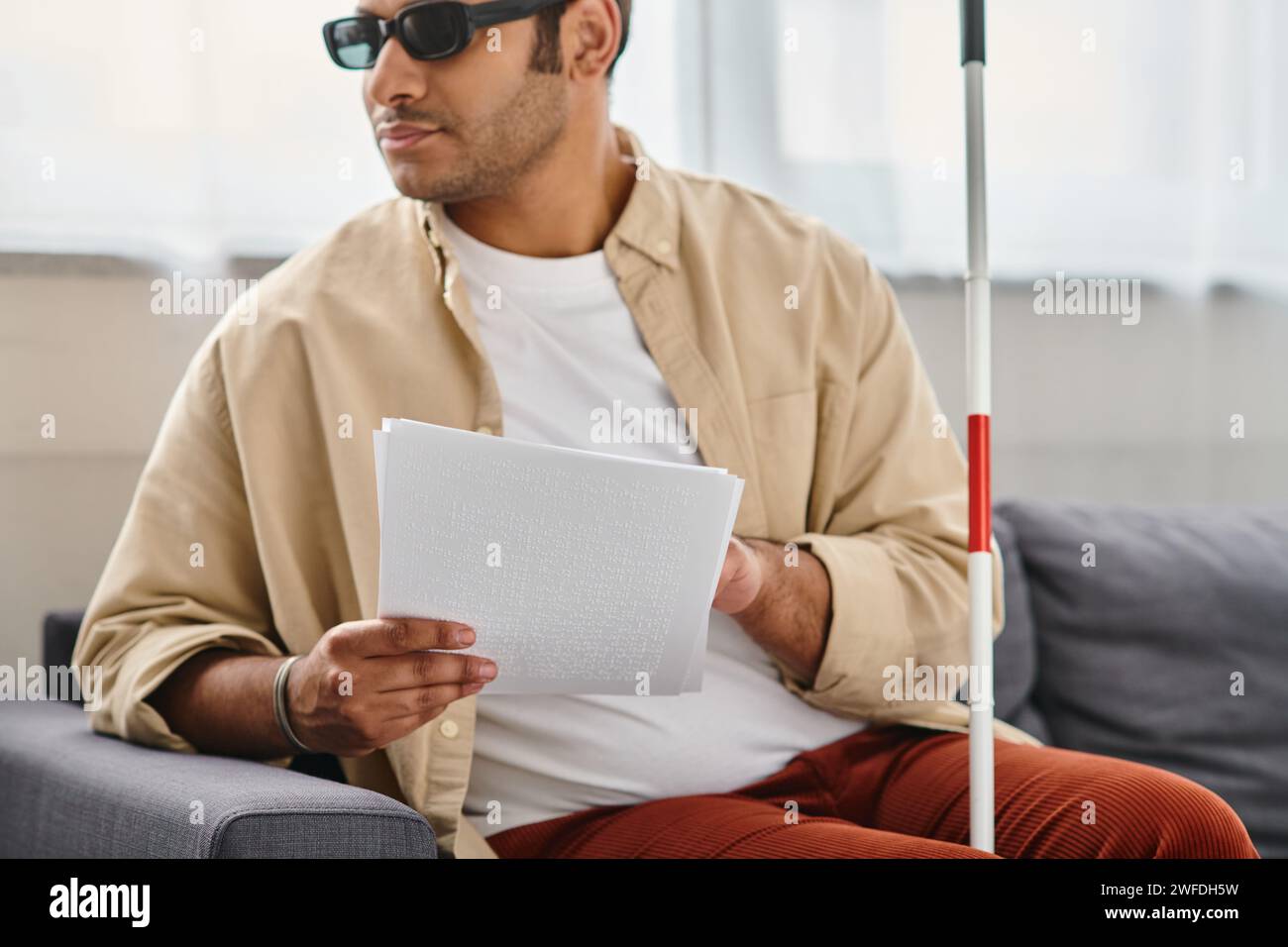 allegro indiano con disabilità visiva con occhiali e bastone da passeggio che legge il codice braille Foto Stock