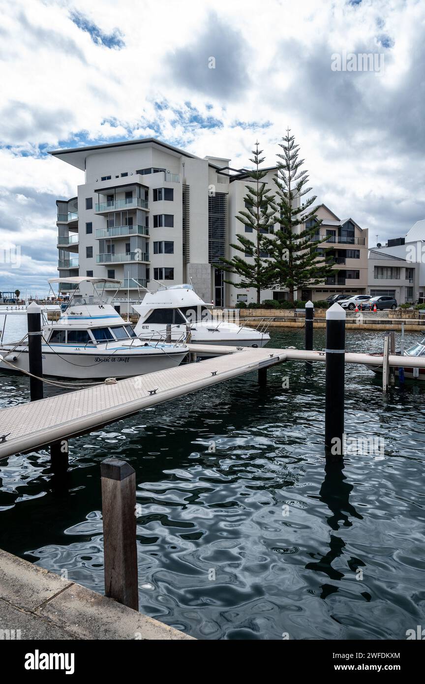 Uno dei molti appartamenti a Mandurah, sulla costa dell'Australia Occidentale, con un porticciolo in primo piano e due barche da pesca sportive ormeggiate. Foto Stock