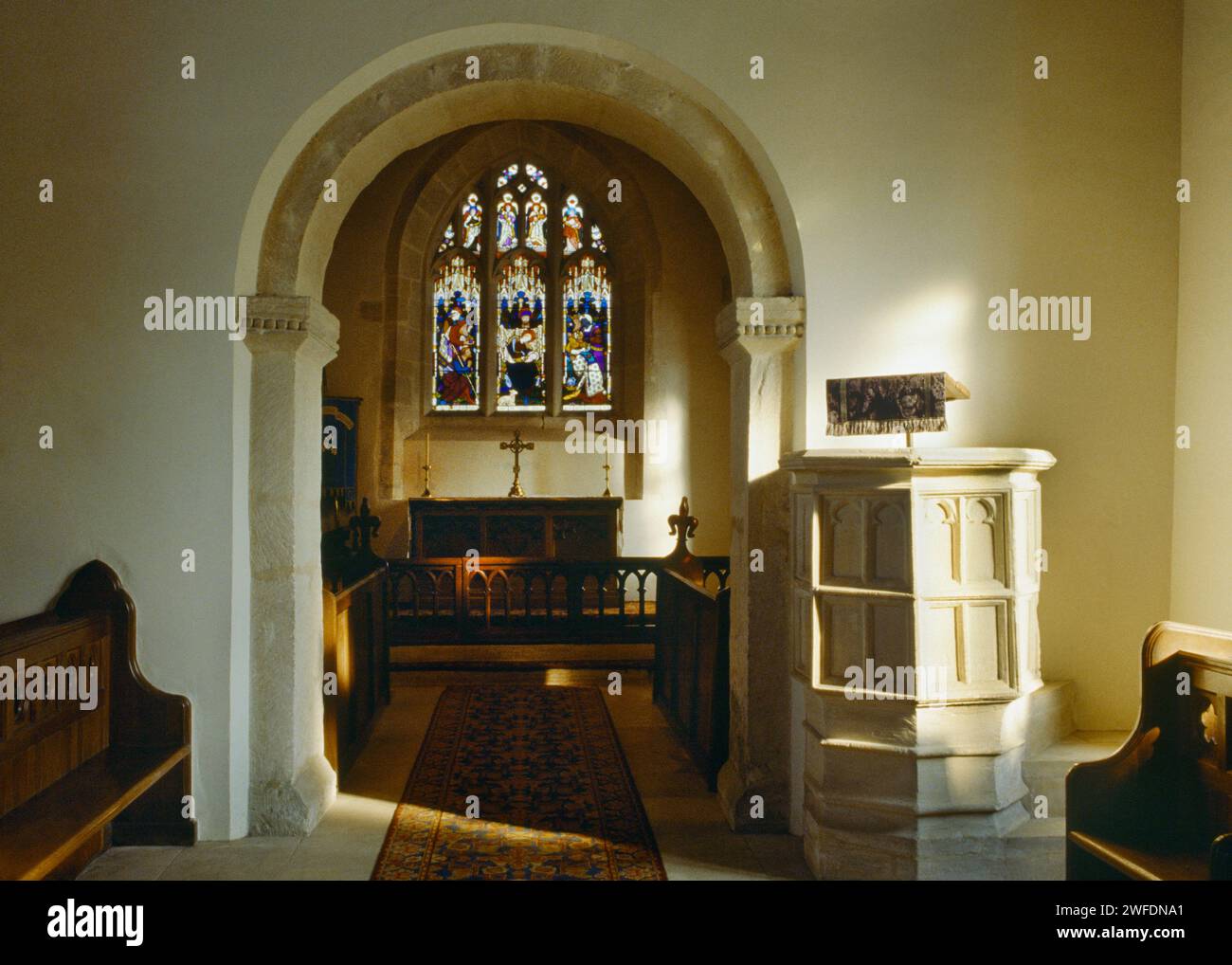 Vista interna della chiesa di St Andrew, Coln Rogers, Gloucestershire, Inghilterra, Regno Unito, mostra il pulpito in pietra C15th accanto all'arco del coro sassone Foto Stock