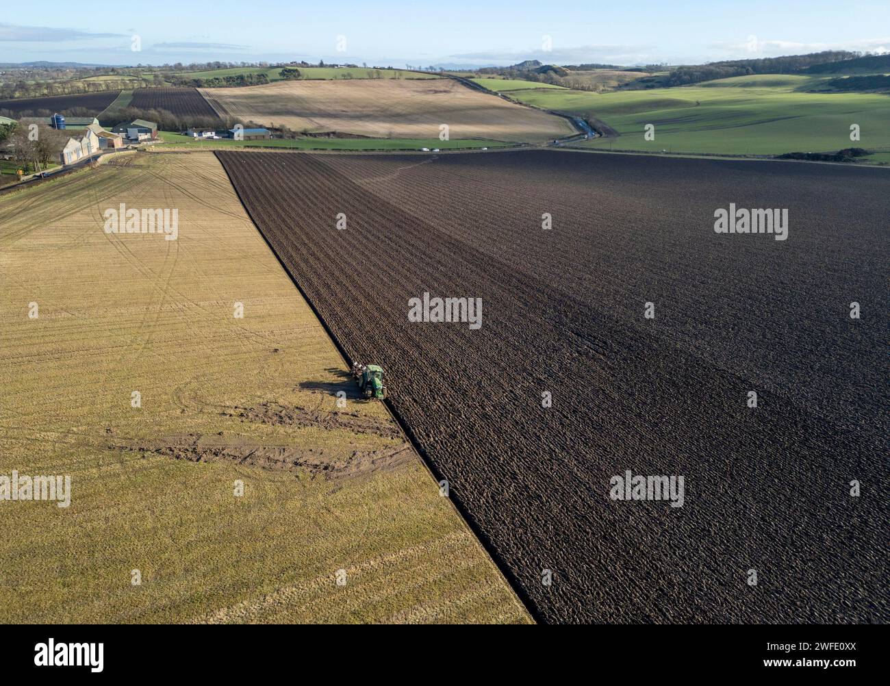 Vista aerea con droni di un trattore che ara un campo, Linlithgow, West Lothian, Scozia Foto Stock