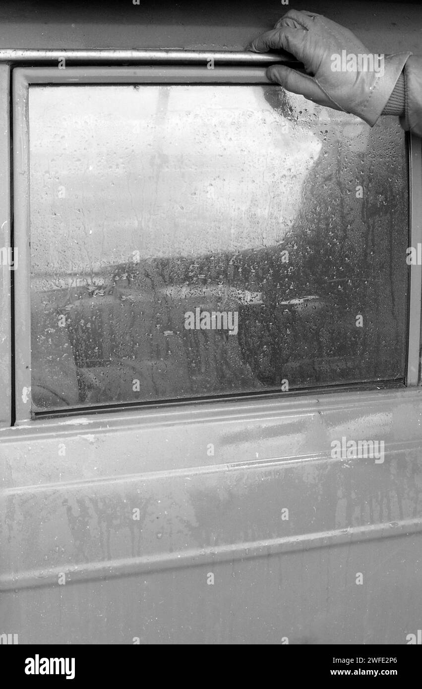 anni '1970, storico, una mano con guanti sulla parte superiore del finestrino di un'auto bagnata. Foto Stock