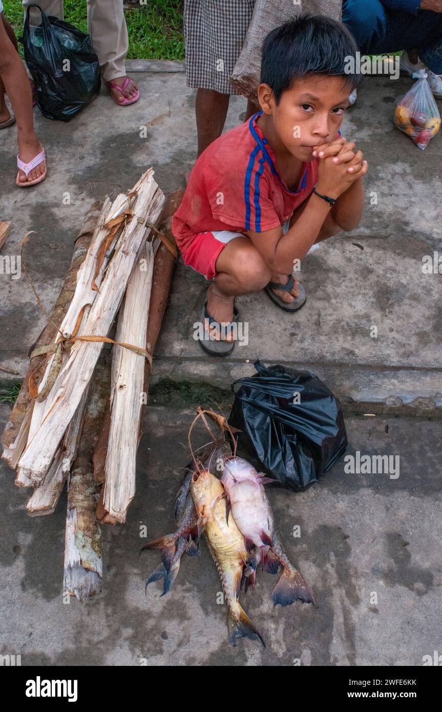 Un ragazzo vende legna da ardere e pesce al mercato di viallage dell'Indiana, Iquitos, Loreto, Perù Foto Stock