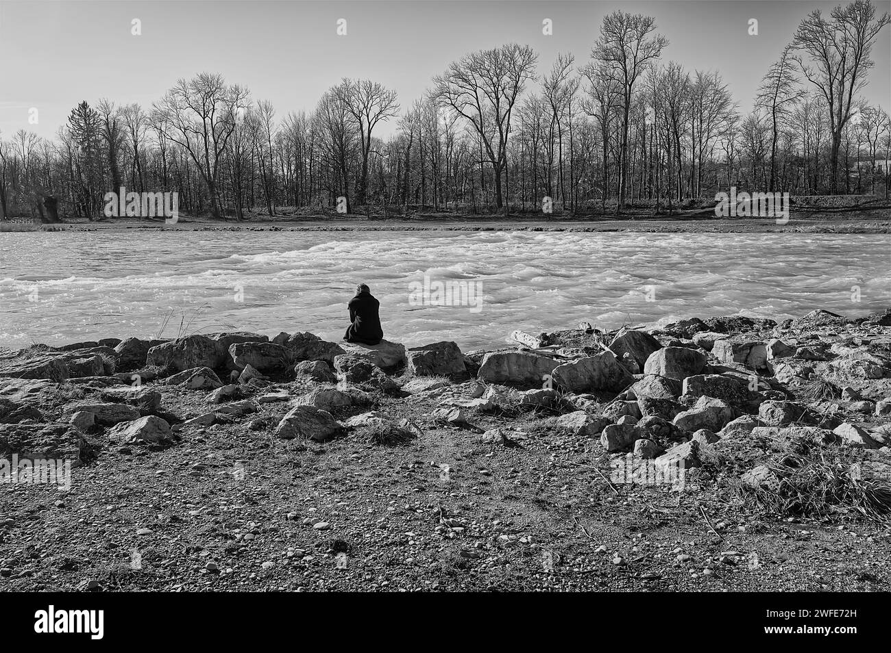 Vista posteriore di una donna seduta da sola sul fiume Foto Stock
