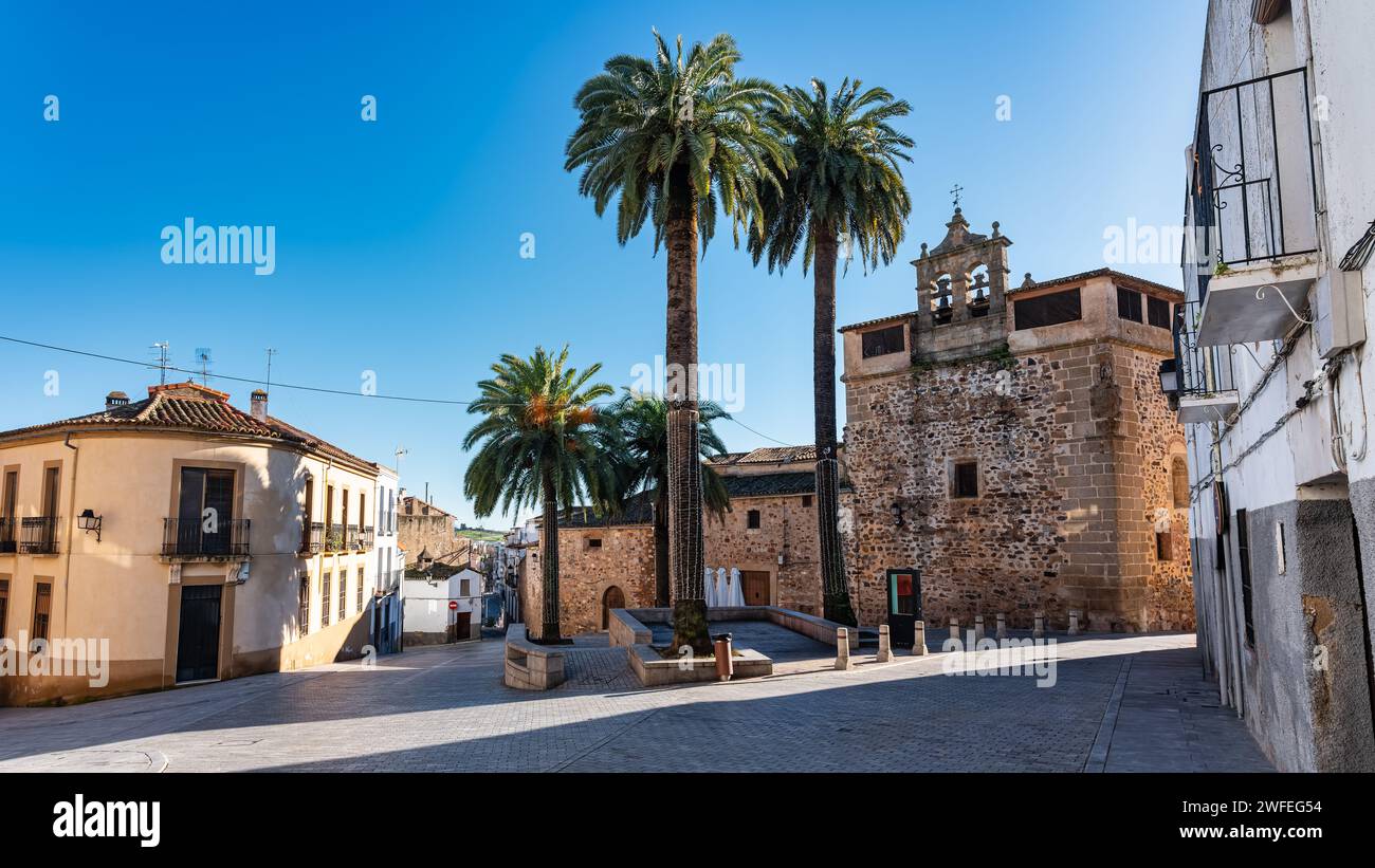 Piazza circondata da palme e vecchia chiesa nella monumentale città di Caceres, Spagna. Foto Stock