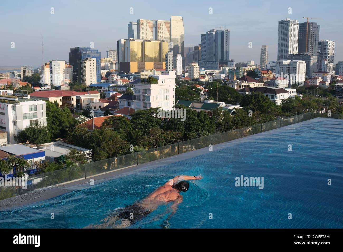 Uomo che nuota in una piscina sul tetto, nel centro di Phnom Penh, Cambogia Foto Stock