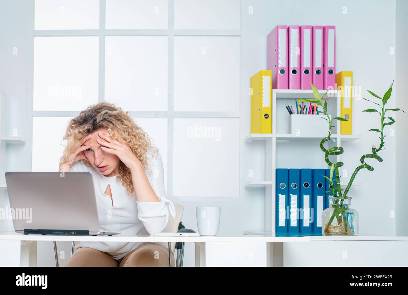 Donna d'affari stanca e addormentata alla scrivania con un computer portatile. Lavoratore in ufficio stanco. Foto Stock