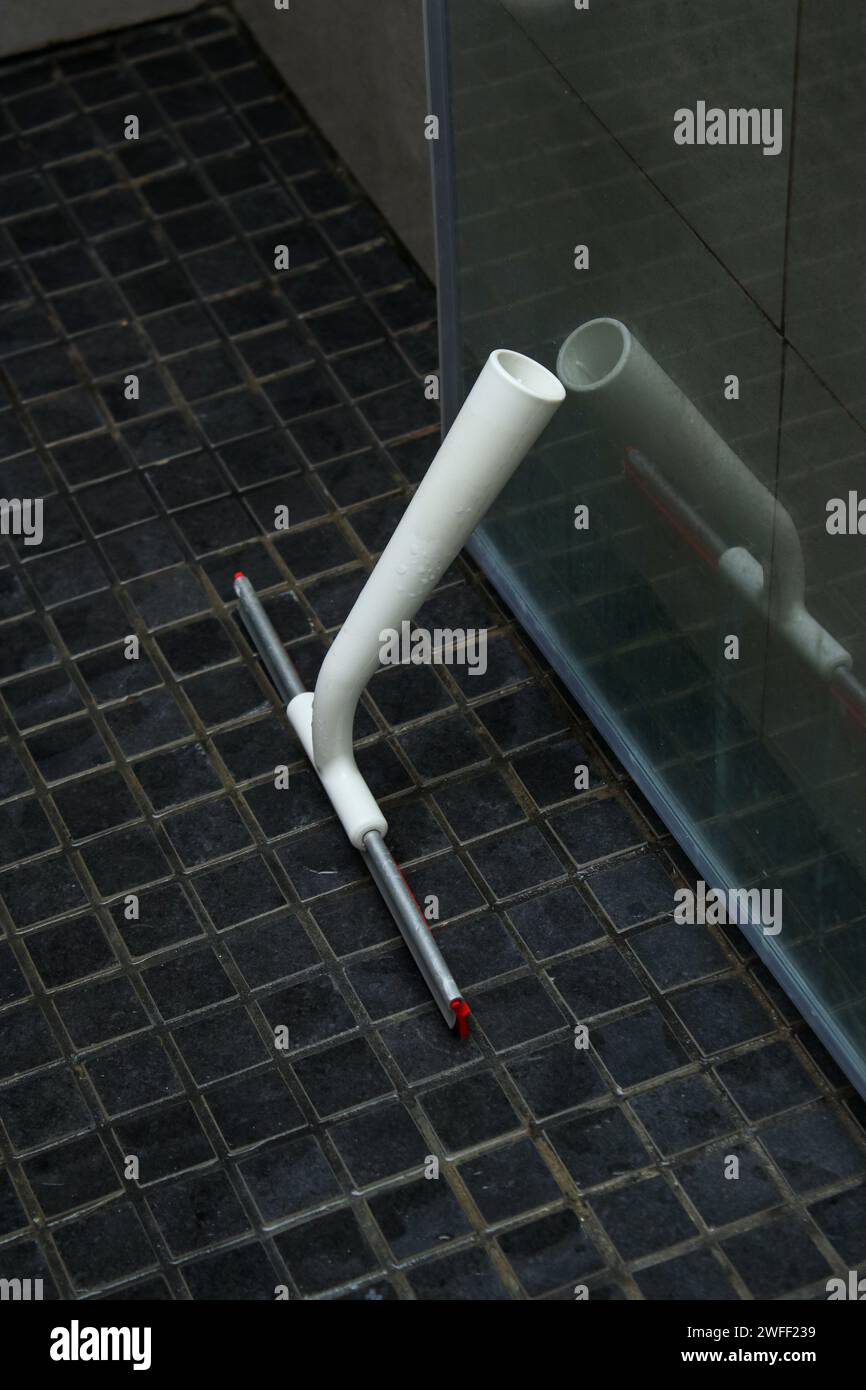 Un panno doccia in plastica sul pavimento della doccia con sporcizia porta in vetro calcareo Foto Stock